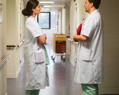 Un médecin femme et un médecin homme en train d'échanger dans un couloir