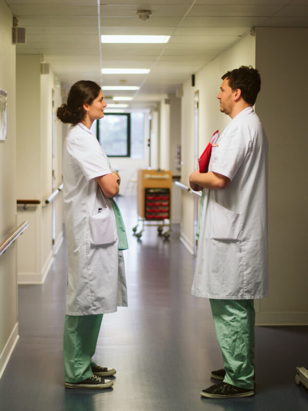 Un médecin femme et un médecin homme en train d'échanger dans un couloir
